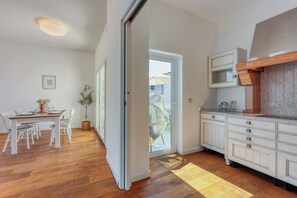 A modern kitchen with white cabinetry, a wooden countertop, and a dining area with a table and chairs. - The Perfect View Penthouse Design Apt. (Mali Losinj)