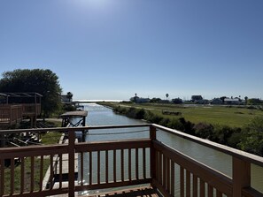 A wooden deck with a view of a canal and distant houses. - Sunrise Breeze: waterfront escape with peaceful views and easy coastal living (Rockport)