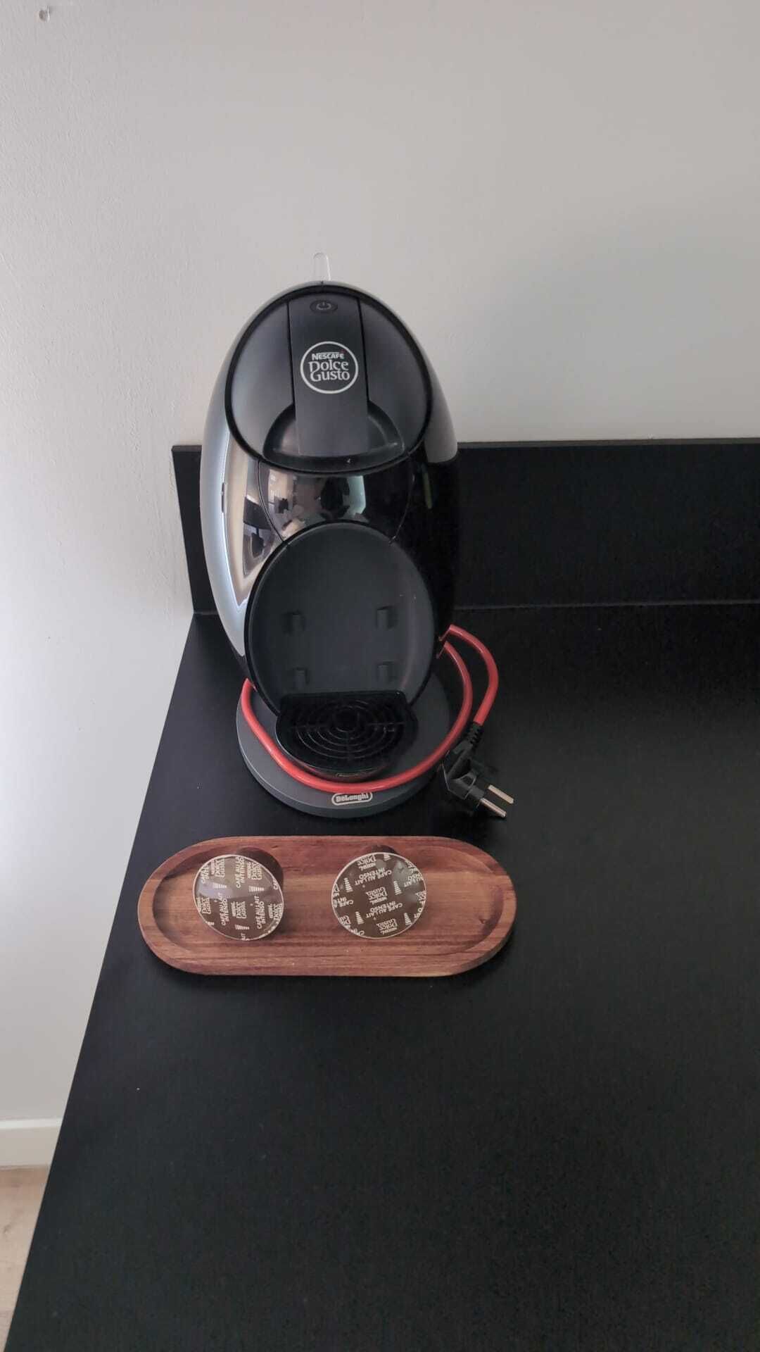 A black coffee maker with a red cord on a black table.