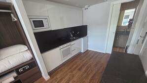 Una cocina compacta con armarios blancos, una encimera negra, un microondas integrado y un horno pequeño.