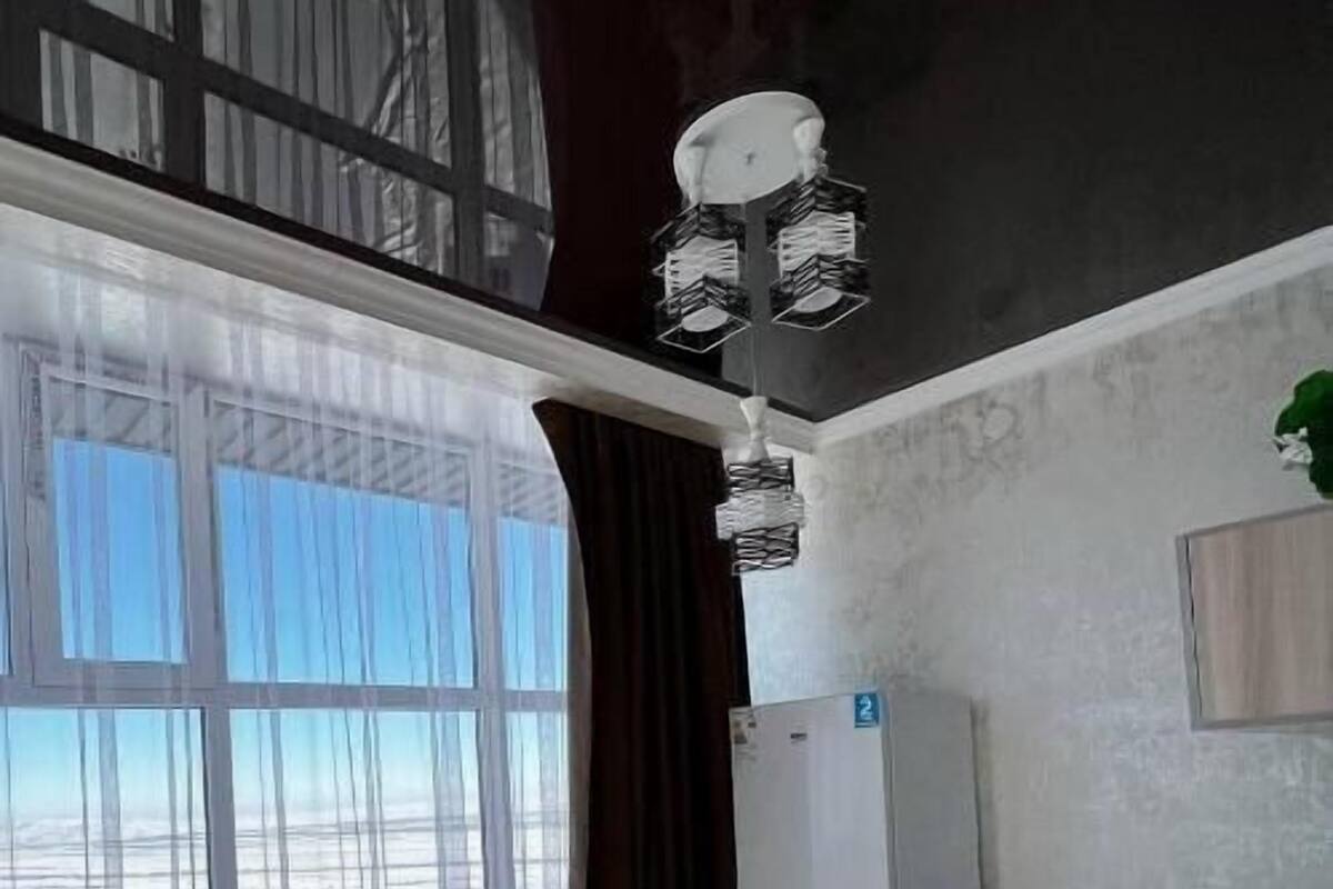 Eine moderne Küche mit großem Fenster, einem weißen Kühlschrank und einer Bar.