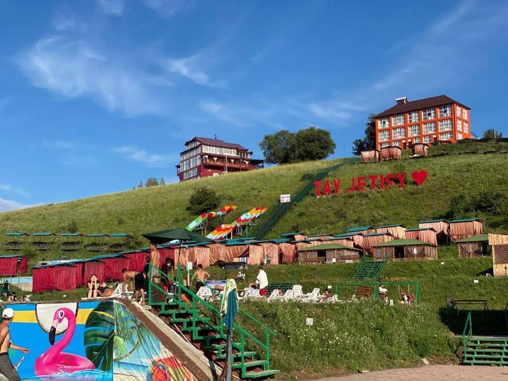 A hotel with a red facade, located on a grassy hill with a clear blue sky.