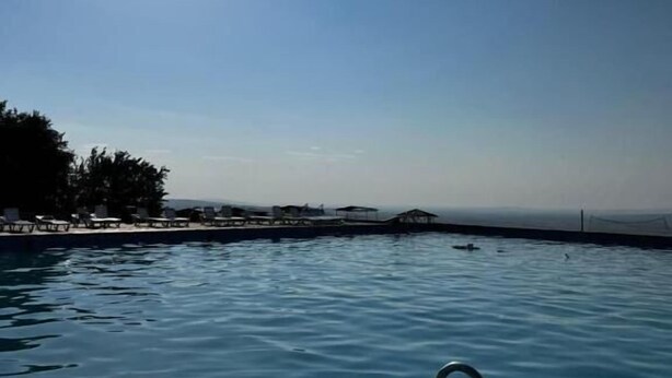 A swimming pool with clear blue water, a sunlit sky, and a view of the horizon. - Tau Zhetysu (Yepkindi)