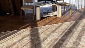 A room with a large window, a desk with a computer, two chairs, and a patterned carpet. - Tau Zhetysu (Yepkindi)