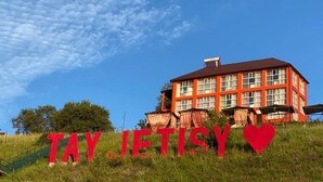 A red building with the text "TAY JETISY" and a heart symbol. - Tau Zhetysu (Yepkindi)