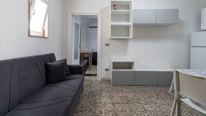 En moderne stue med en mørkegrå sofa, et hvidt væghængt skab og et lille bord med en stol.