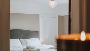 A hotel room with a bed, a nightstand, and a hanging light fixture.