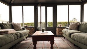 A cozy room with two green sofas, a plaid rug, and a wooden coffee table.
