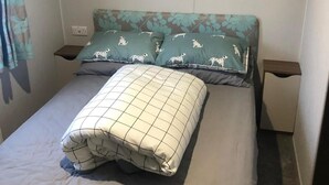 Ein Bett mit einem gemusterten Kopfkissen, einem schlichten Kopfkissen und einem Blumenmuster an der Kopfteil.
