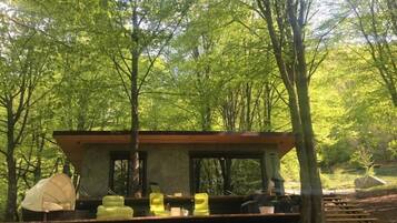 Una estructura de madera rústica con un banco y una mesa, rodeada de árboles.