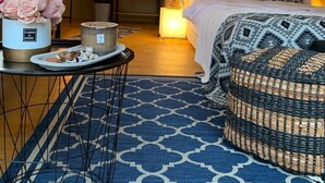 Une chambre confortable, aménagée comme une tente, avec un lit, une table de chevet et un tapis à motifs.