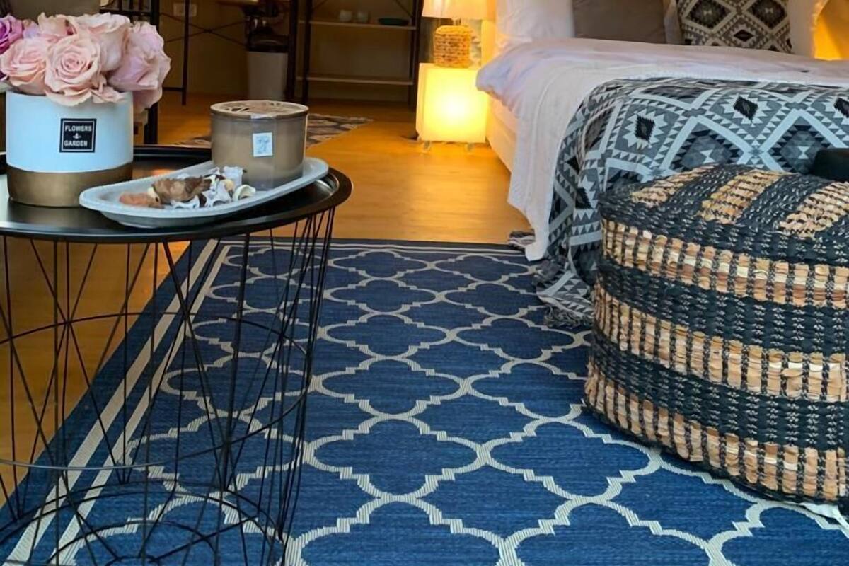 A cozy, tent-style bedroom with a bed, bedside table, and a patterned rug.