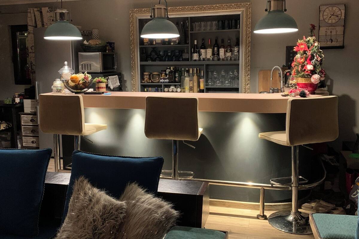 A bar area with a counter, bar stools, and pendant lighting.