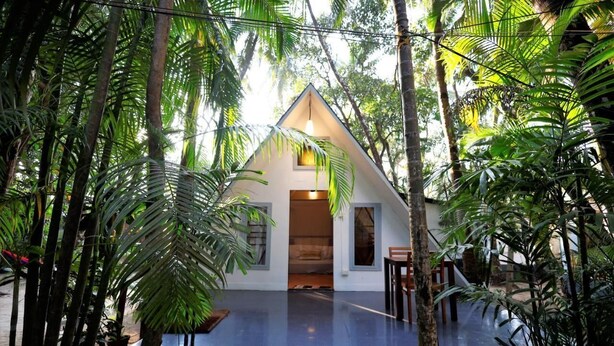 A modern house with a triangular roof, surrounded by lush tropical vegetation. - Temple Garden (Canacona)