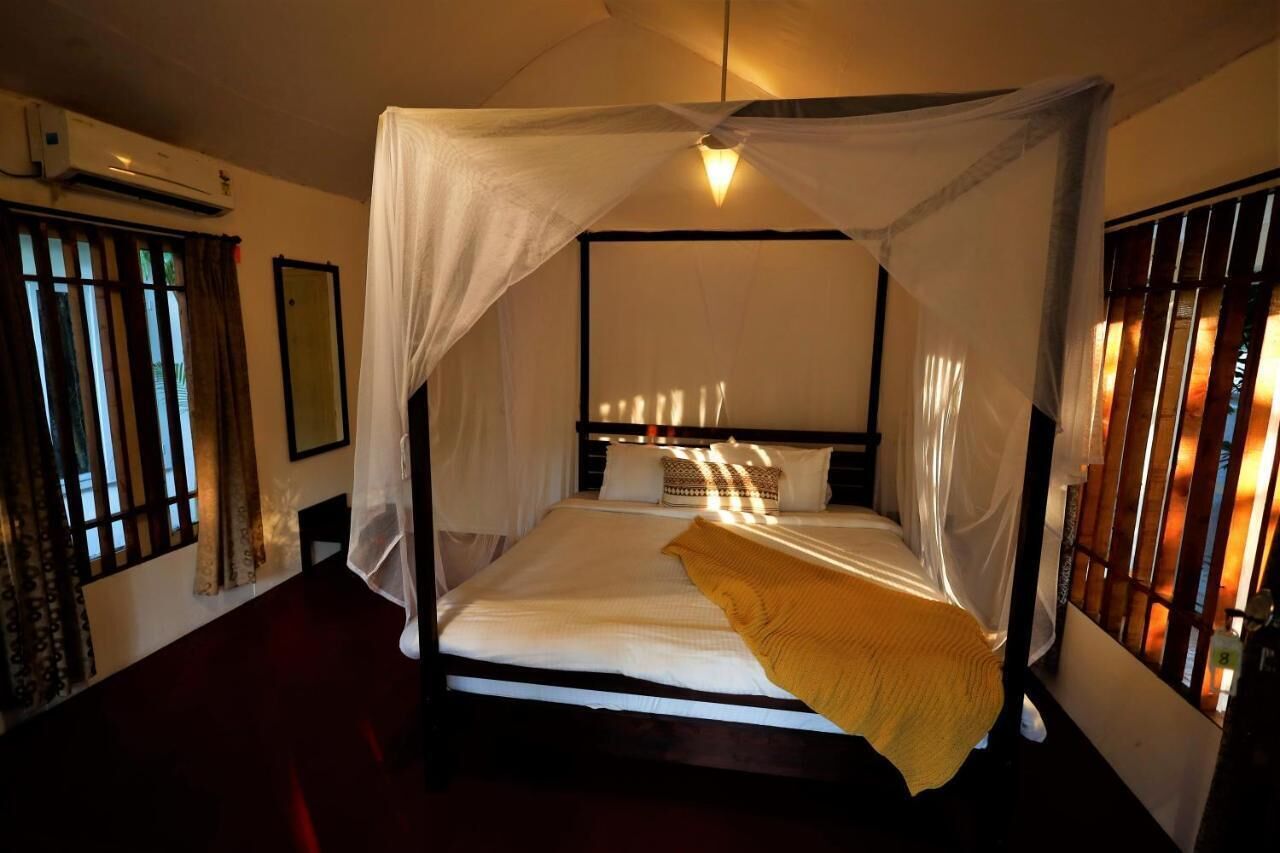 A four-poster bed with a canopy, a bedside table, and a wall-mounted air conditioning unit.