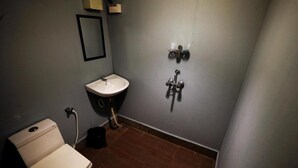 A small bathroom with a toilet, sink, and shower. - Temple Garden (Canacona)