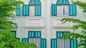 A building with multiple windows, each with white frames and green shutters. - V&T Hotel Phu Quoc (Phu Quoc)