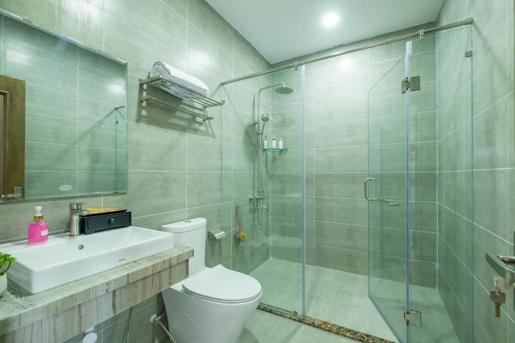 Un baño moderno con ducha de vidrio, lavabo blanco y retrete.