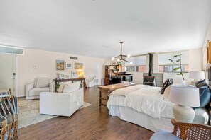 Ein geräumiges Wohnzimmer mit einem großen Bett, einem Essbereich und einer Küche im Hintergrund.