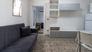 Een moderne woonkamer met een donkergrijze bank, een bijzettafeltje en inbouwplanken.