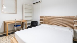 Een slaapkamer met een bed, een bureau, een stoel en een kledingkast.