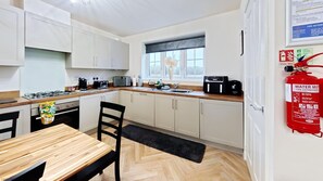 A modern kitchen with white cabinets, a wooden countertop, and a black chair.