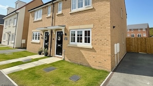 A two-story residential building with a brick facade, a front door with a wreath, and a small front garden.