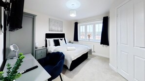 A hotel room with a bed, bedside table, chair, desk, and a window with curtains.