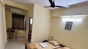 Ein Hotelzimmer mit zwei Betten, einem Schreibtisch und einem Deckenventilator.