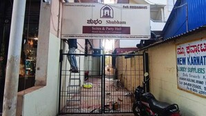 Ein verschlossenes Tor zu einem Anwesen namens Shubham Suites & Party Hall, mit einem Motorrad davor.