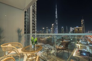 A balcony with wicker furniture, a glass table, and a potted plant. The view includes the Burj Khalifa and other Dubai skyline buildings. - Vida Dubai Mall Balcony with Burj & City Views – Walk to Dubai Mall by Heaven Crest Vacation Homes (Dubai)