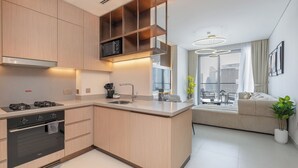 A modern kitchen with integrated appliances, a dining area with a view, and a living space with a sofa and a plant. - Vida Dubai Mall Balcony with Burj & City Views – Walk to Dubai Mall by Heaven Crest Vacation Homes (Dubai)