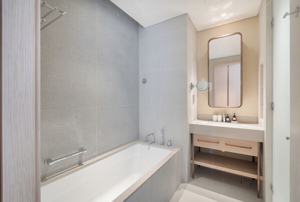 A modern bathroom with a large bathtub, a shower, and a vanity with a mirror. - Vida Dubai Mall Balcony with Burj & City Views – Walk to Dubai Mall by Heaven Crest Vacation Homes (Dubai)