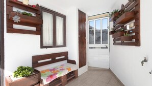 A narrow corridor with a wooden bench, a door, and wooden shelves with plants. - Holiday Home 'D´Aldeia' with Shared Terrace, Private Garden and Wi-Fi (Cela Velha)