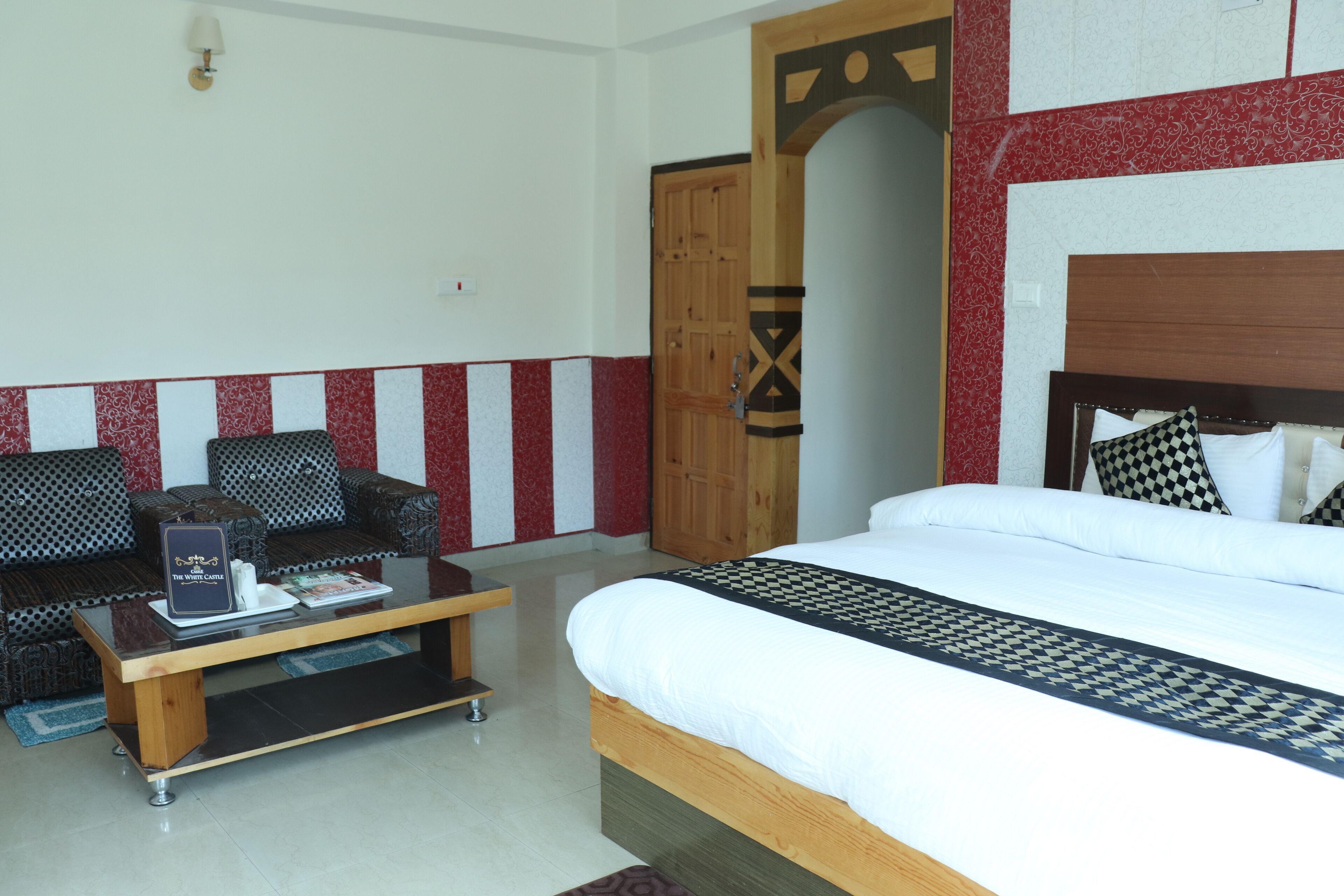 A hotel room with a bed, a sofa, a coffee table, and a wooden wardrobe.