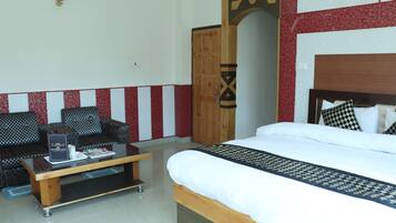 A hotel room with a bed, a sofa, a coffee table, and a wooden wardrobe.