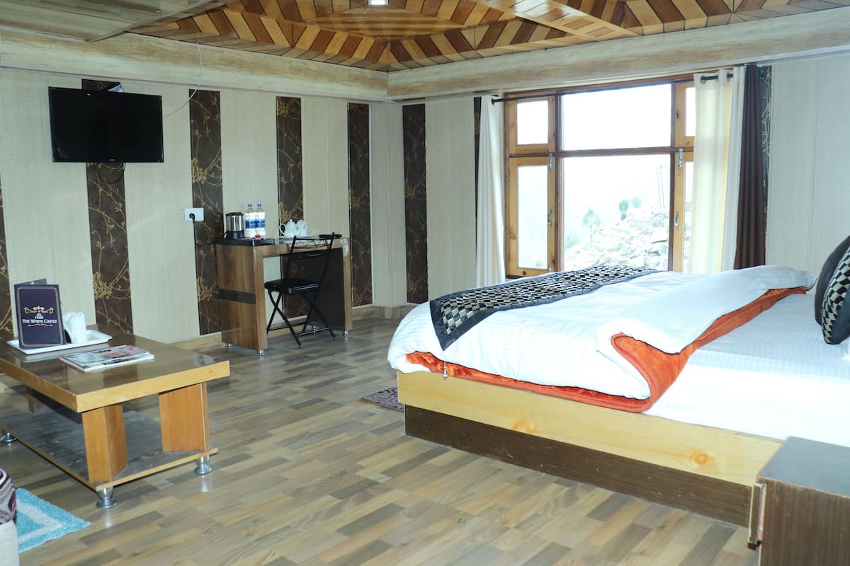 A hotel room with a bed, a desk, a TV, and a window with curtains.