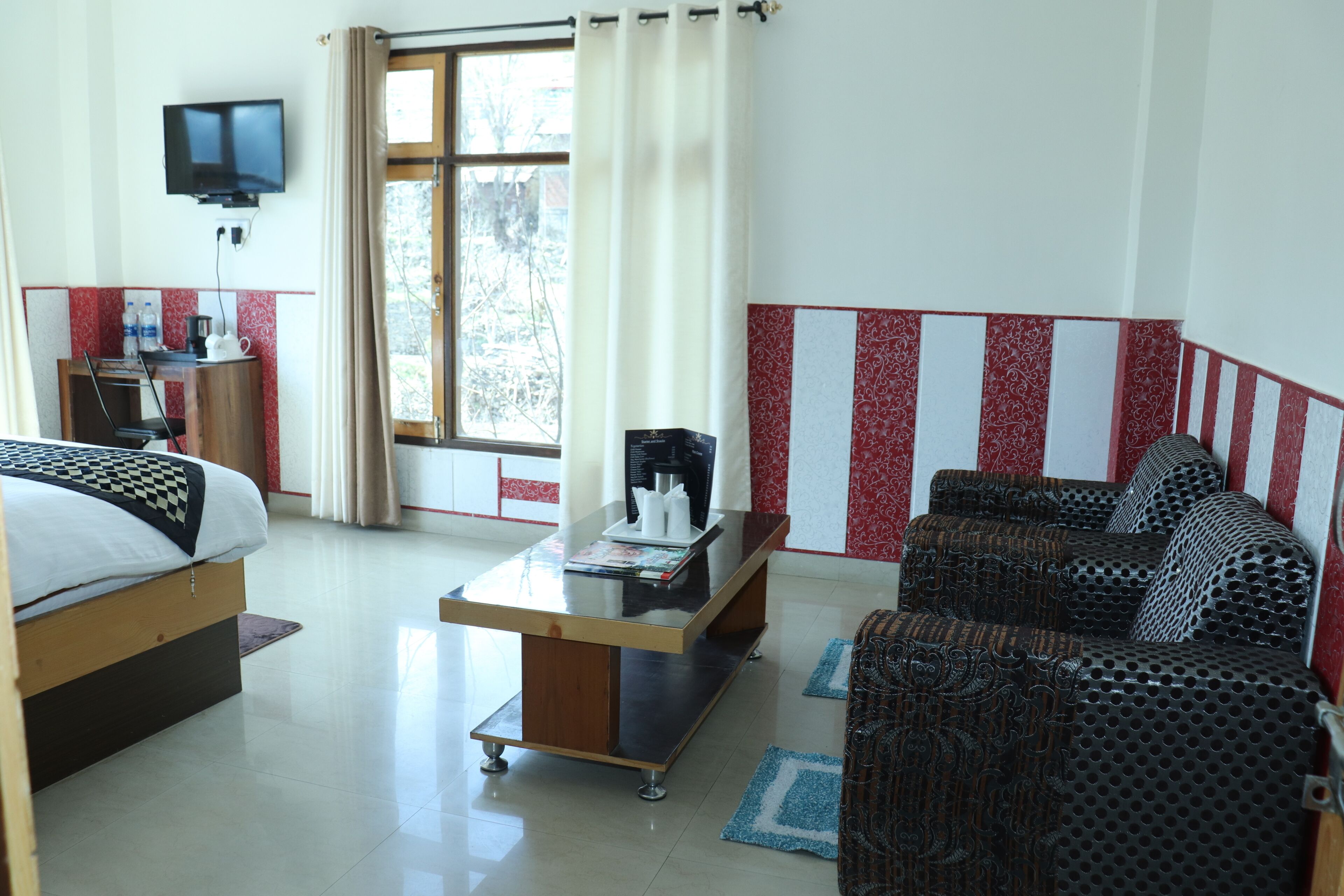 A hotel room with a bed, a sofa, a coffee table, a TV, and a desk with a chair.