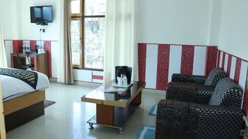 A hotel room with a bed, a sofa, a coffee table, a TV, and a desk with a chair.