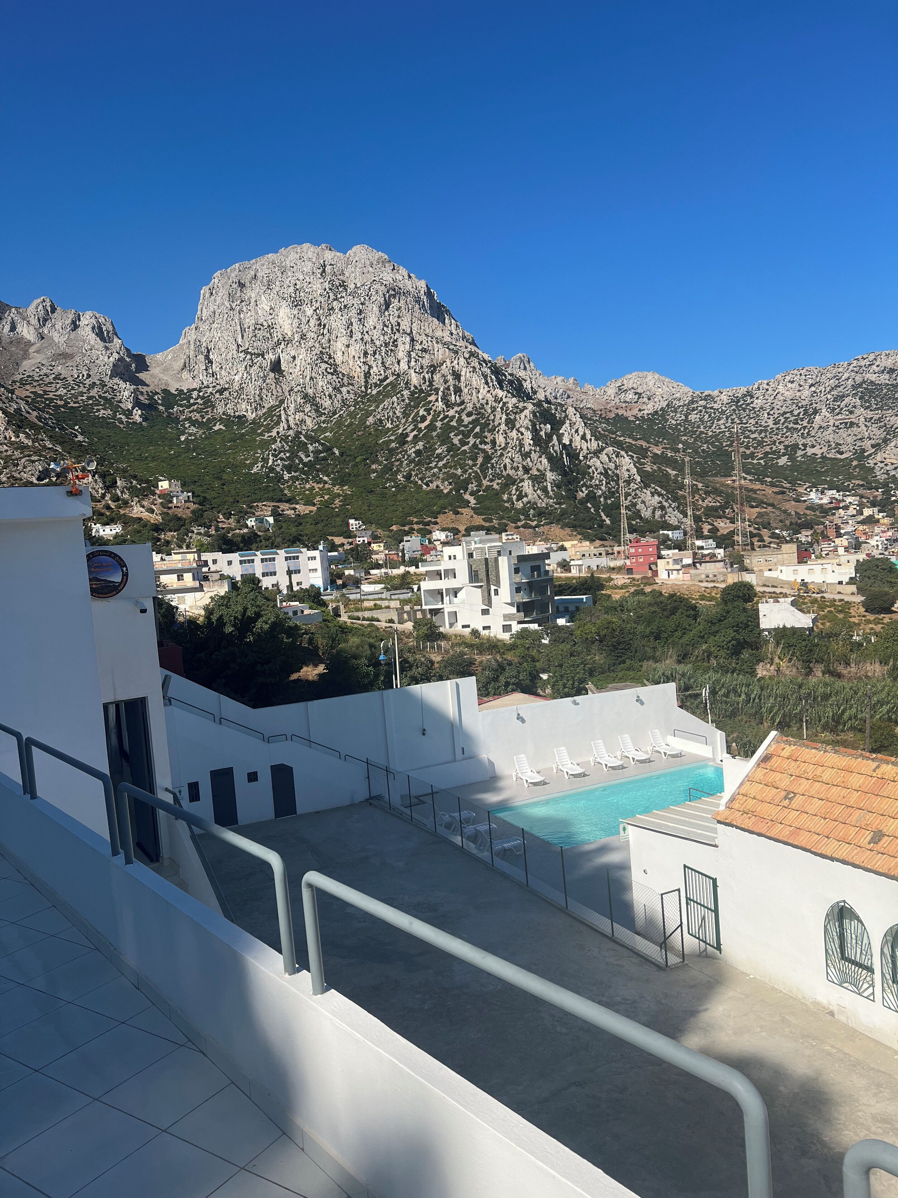 Une piscine sur le toit offrant une vue sur un paysage montagneux et sur la ville située en contrebas.