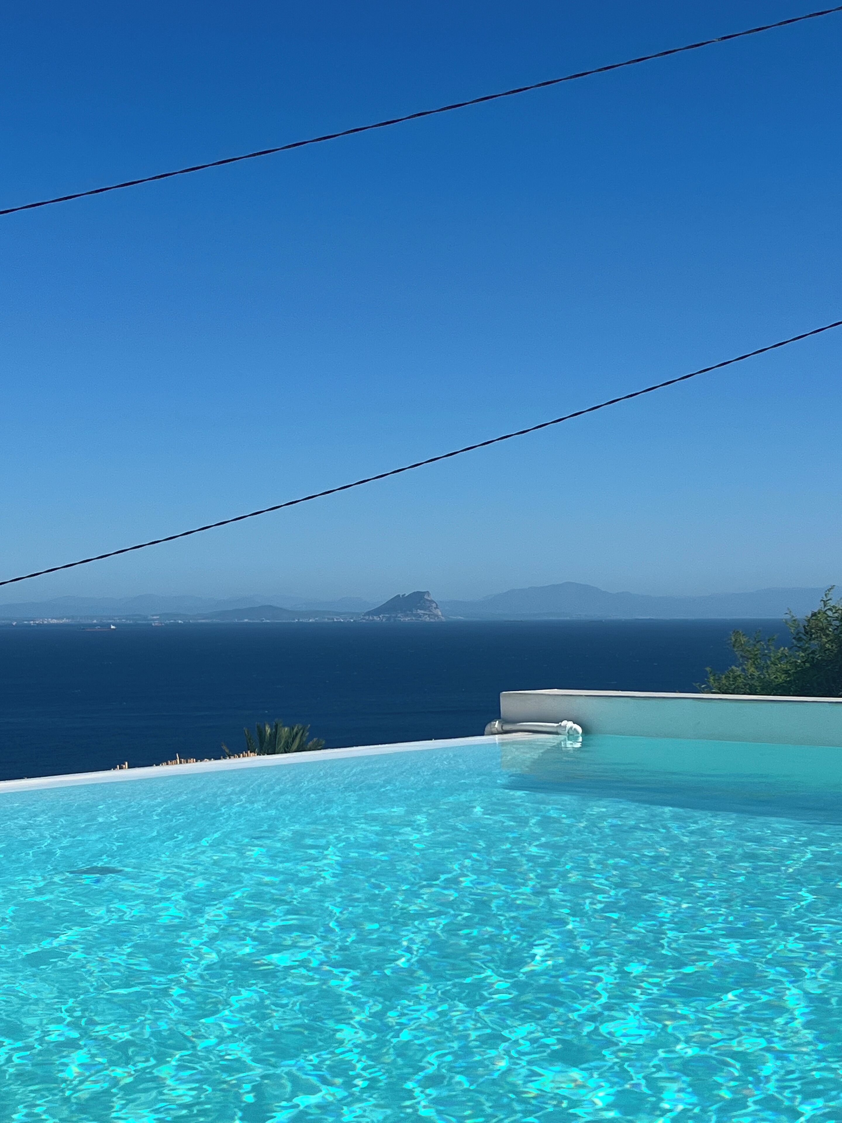 Ein klarer, blauer Himmel, ein Schwimmbad und ein weiter Blick auf das Meer und die Berge.
