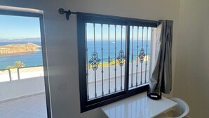 Un balcón con vista al mar y una mesa con dos sillas.