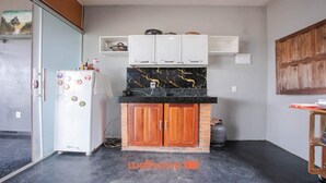 A compact kitchen with a white refrigerator, wooden cabinets, and a black marble backsplash. - Sítio em Jaboticatubas com Área de Lazer Completo (Jaboticatubas)
