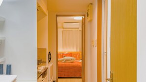 A narrow hallway with a bed at the end, a washing machine, and a door on the right. - Skytree Star 11 Hotel (Tokyo)
