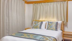 A neatly made bed with a patterned bedspread, a wooden headboard, and a bedside table with a lamp. - Skytree Star 11 Hotel (Tokyo)