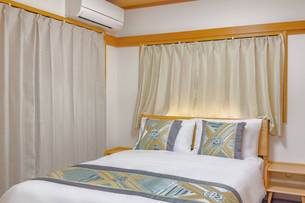 A neatly made bed with a patterned bedspread, a wooden headboard, and a bedside table with a lamp.