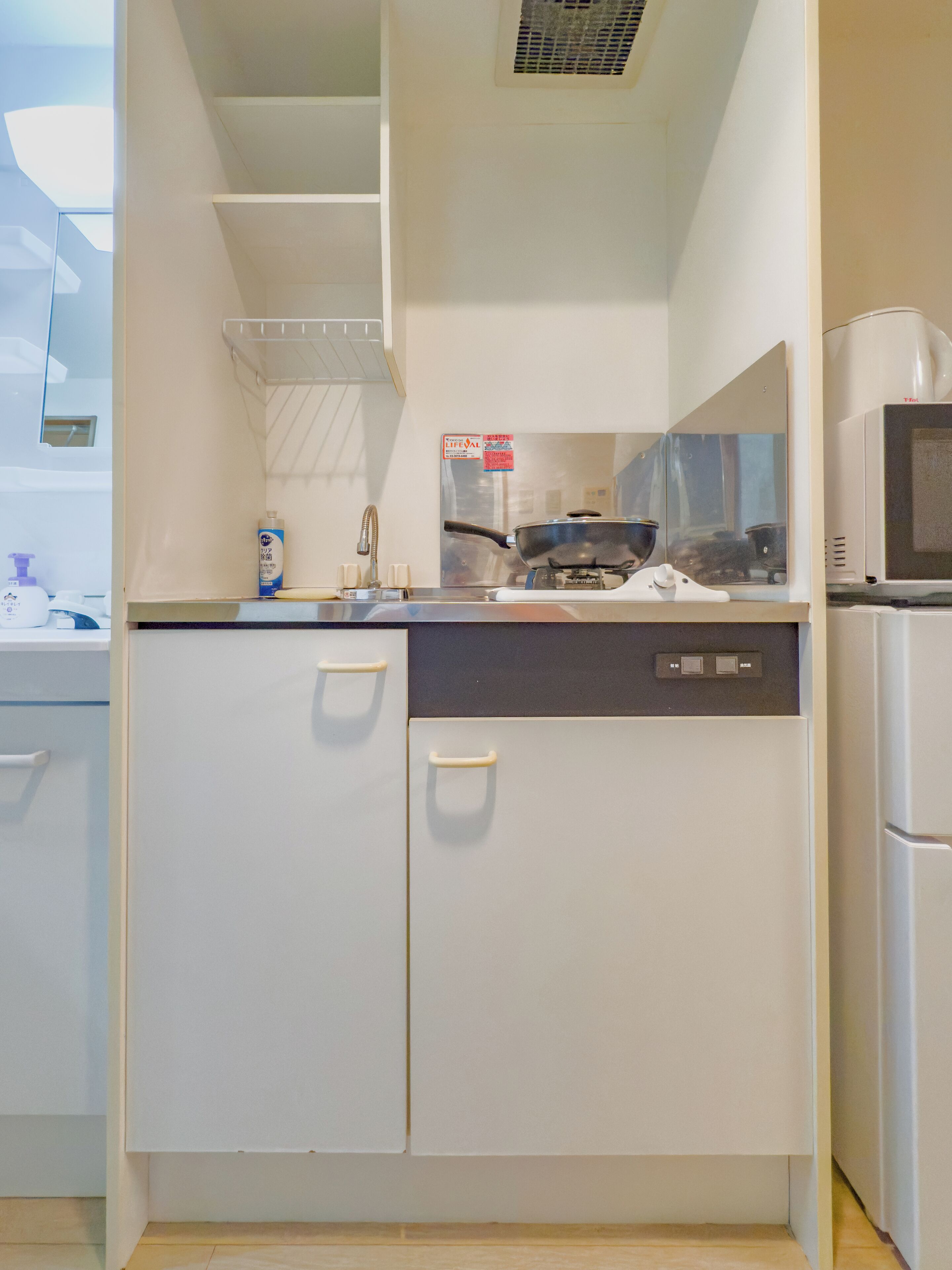 Une cuisine de taille réduite, avec des meubles blancs, un four à micro-ondes et une cuisinière.