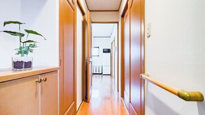 A hallway with wooden doors, a potted plant, and a row of shoes at the end. - Skytree Star 11 Hotel (Tokyo)
