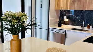 A modern kitchen with a stainless steel refrigerator, wooden cabinets, a marble backsplash, and a white countertop. - Casa Marguerite by Rentallido - Hammam & gymnasium (Caniço)