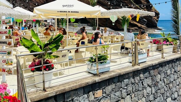 A seaside restaurant with outdoor seating, a stone wall, and a view of the ocean. - Casa Marguerite by Rentallido - Hammam & gymnasium (Caniço)